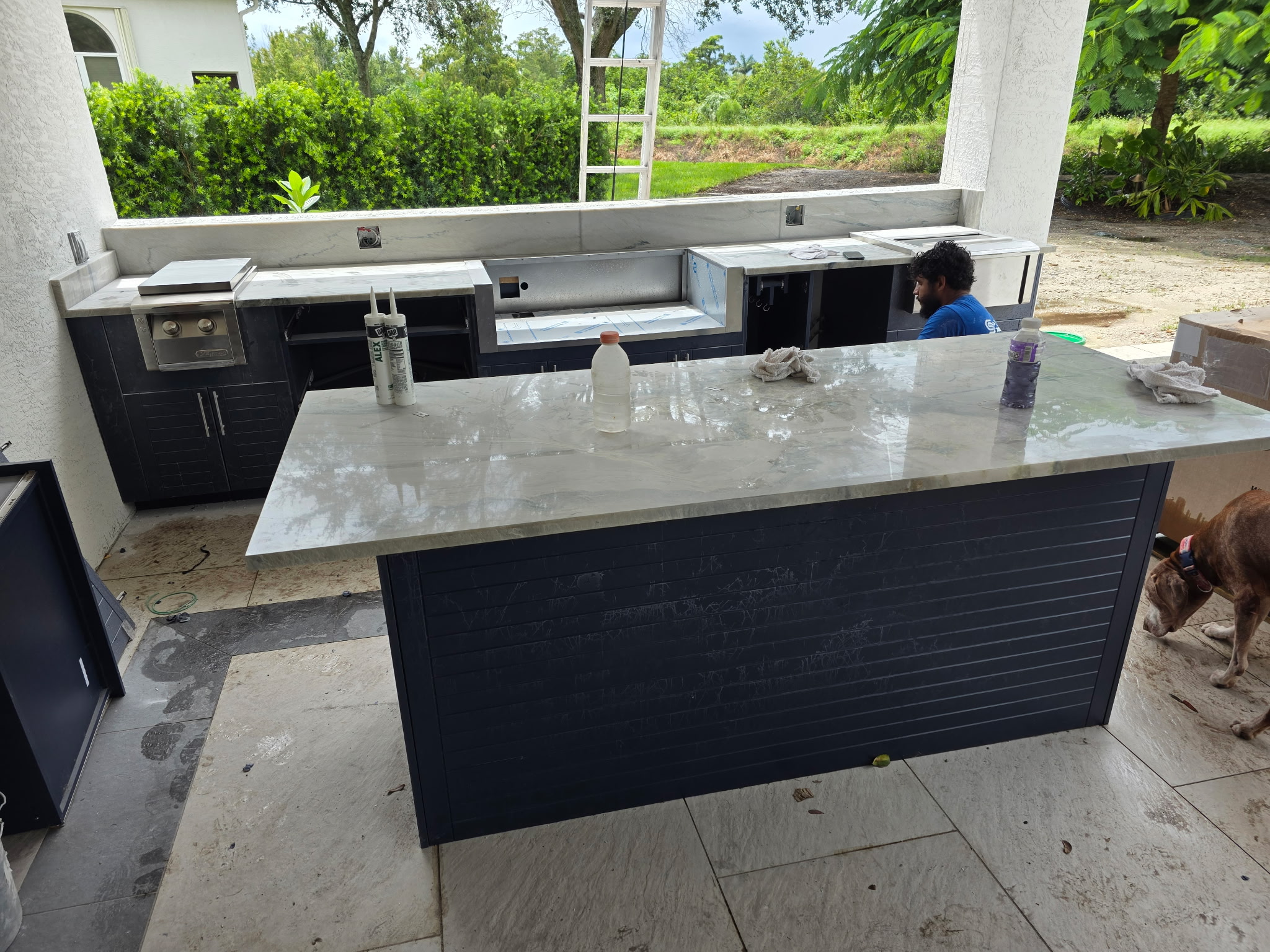 Outdoor kitchen South Florida — navy cabinets quartzite countertops wood ceiling
