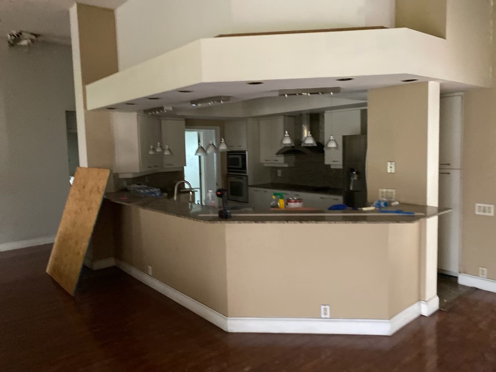 Kitchen before remodel — Parkland FL, closed peninsula layout, dark wood floors, dated granite countertops, soffit ceiling