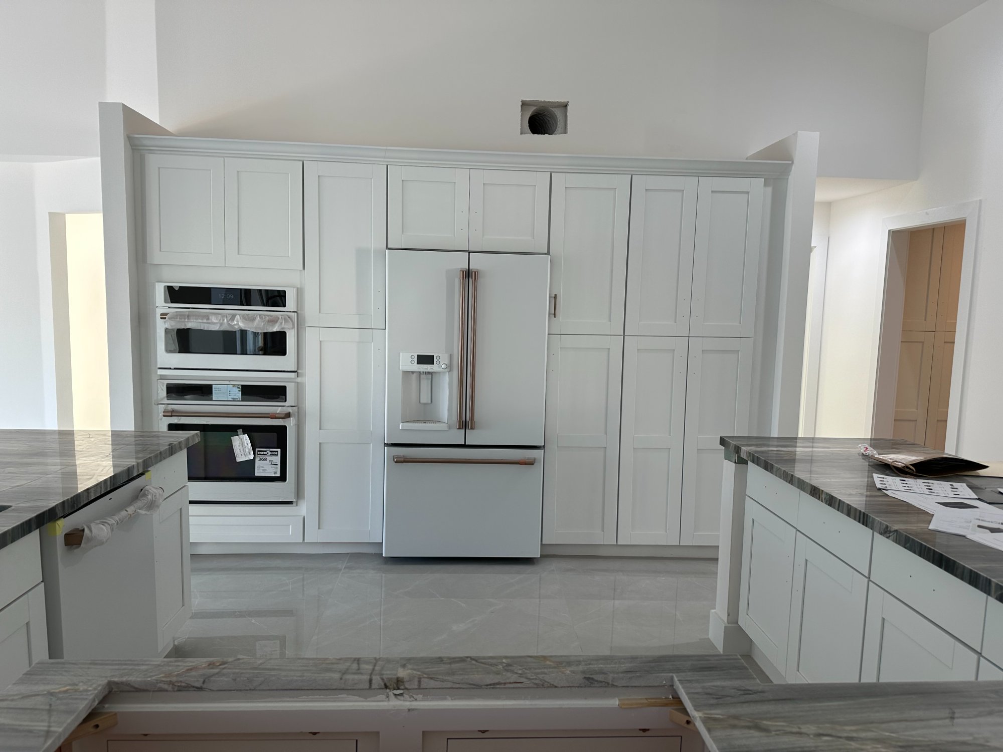 Kitchen after — Café wall ovens and microwave with bronze handles, white shaker cabinet wall