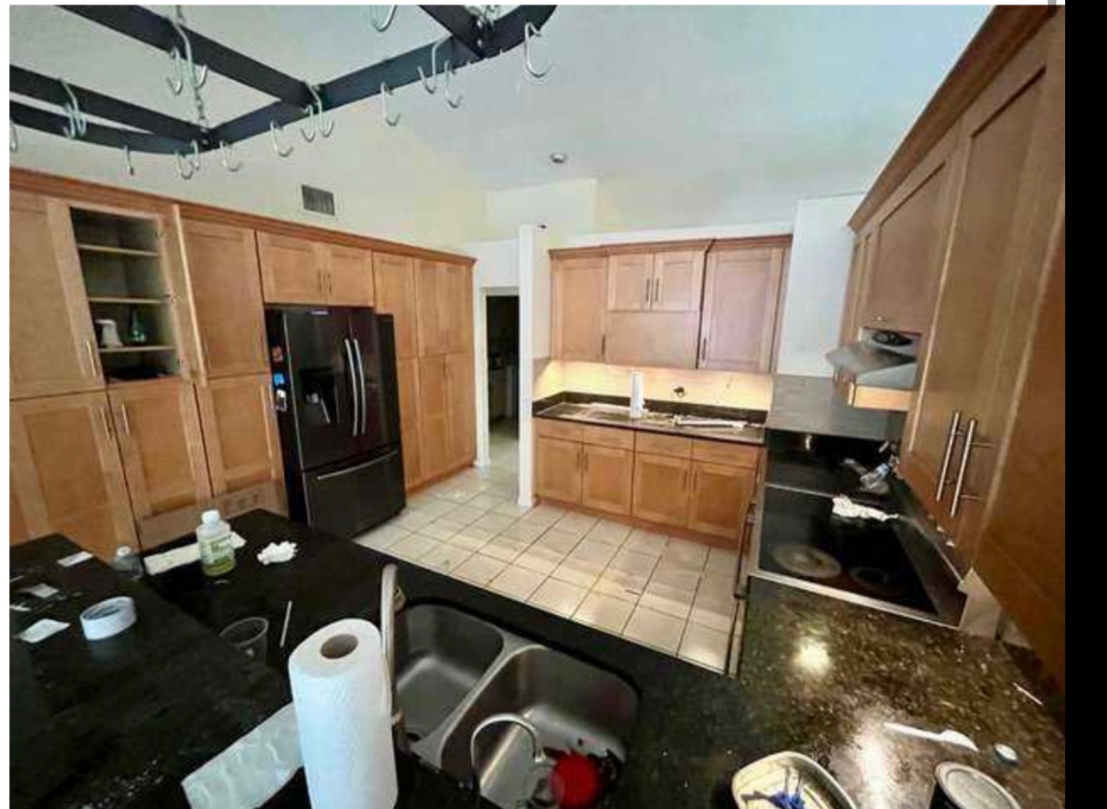 Kitchen before remodel — honey oak cabinets, black granite countertops, dated tile floors