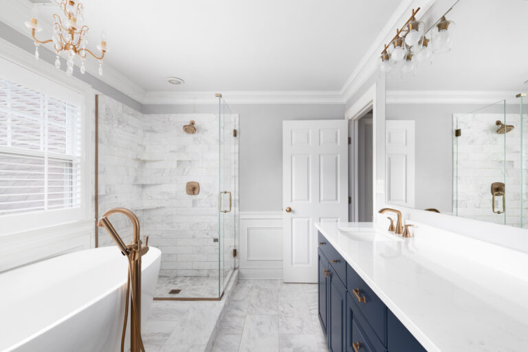 A beautiful remodeled bathroom with a blue vanity cabinet, standalone bath